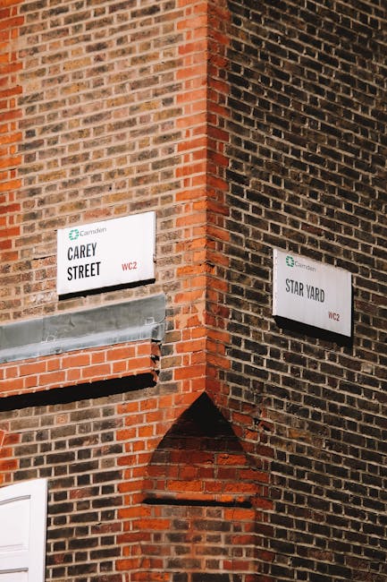 Exterior view of Camden Town Station entrance with a large blue sign displaying 'CAMDEN TOWN STATION' above the doorway. The station is housed in a red brick building with arched windows and a small r